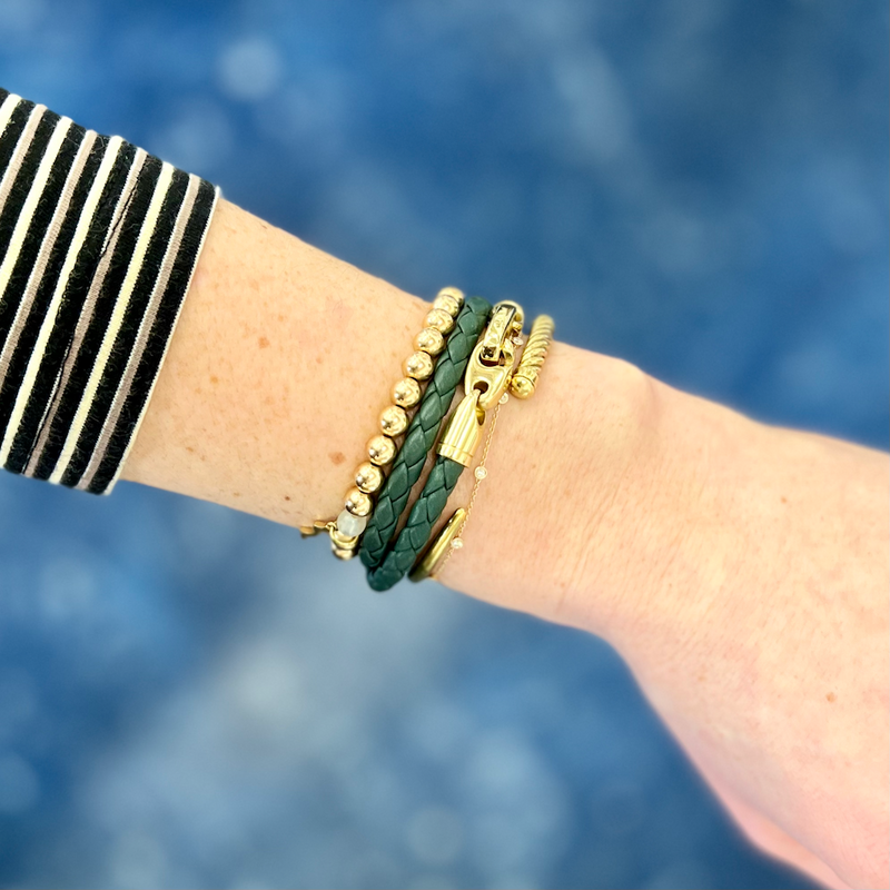 sailormade women's nautical double wrap leather bracelet with polished brass brummels in evergreen stacked with 14k gold fill rayminder uv awareness bracelet and slim fid cuff in satin gold. Handmade in Boston, MA.