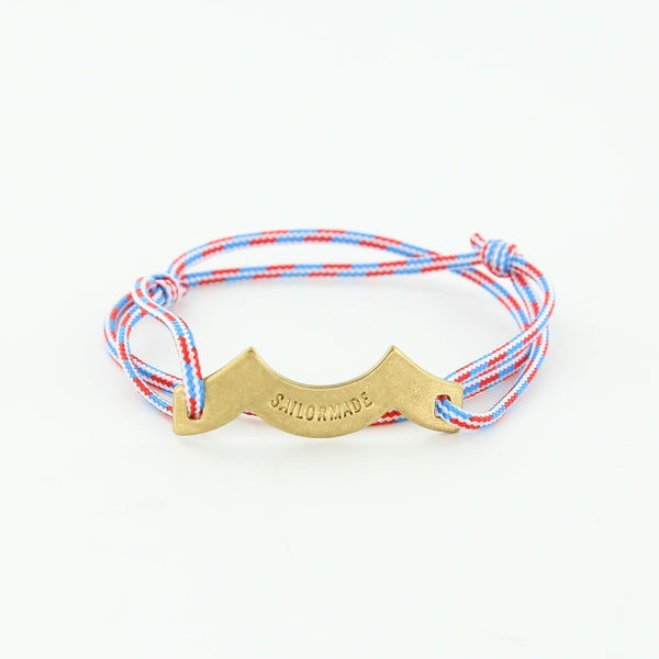 Sporting slip knot rope bracelet with brass wave charm in blue, red, white. Made in Boston.
