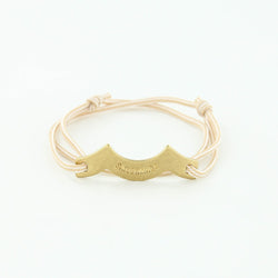 Sporting slip knot rope bracelet with brass wave charm in beige and white. Made in Boston.